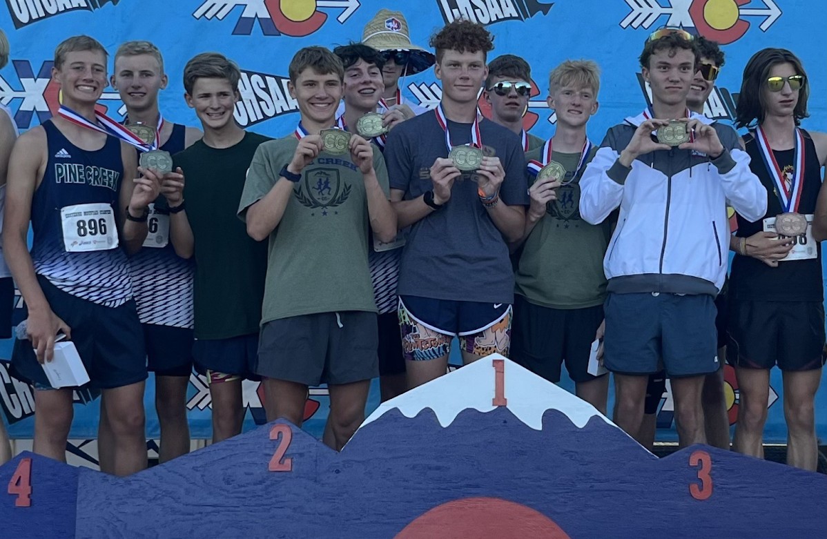 Boys Cross Country team on the podium holding up their medals at the Cheyenne Mountain Stampede. 